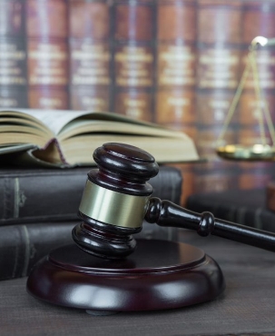 A gavel photographed in front of a stack of legal documents